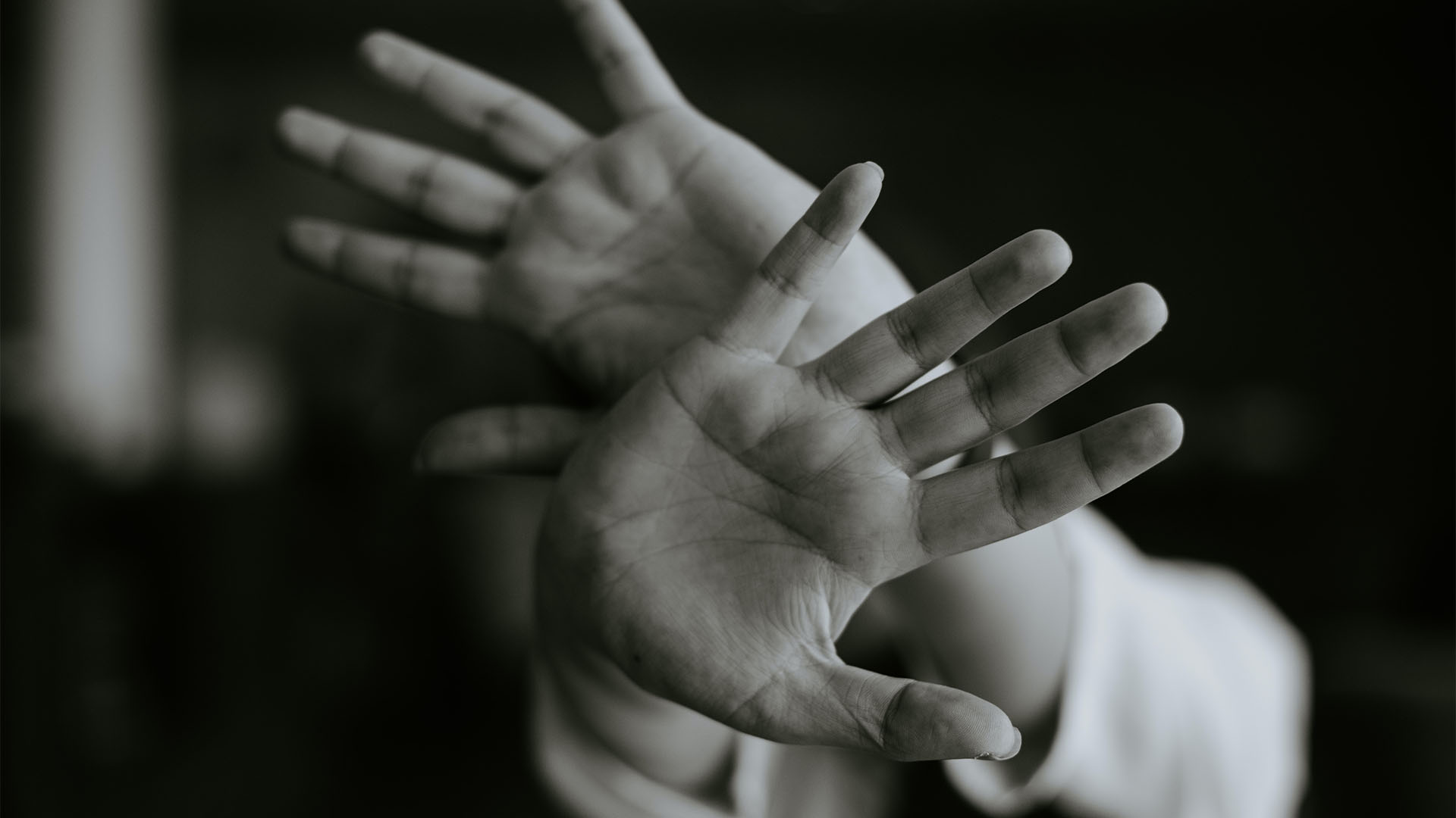 Closeup shot of a pair of hands crossing in the front hiding the person's face.