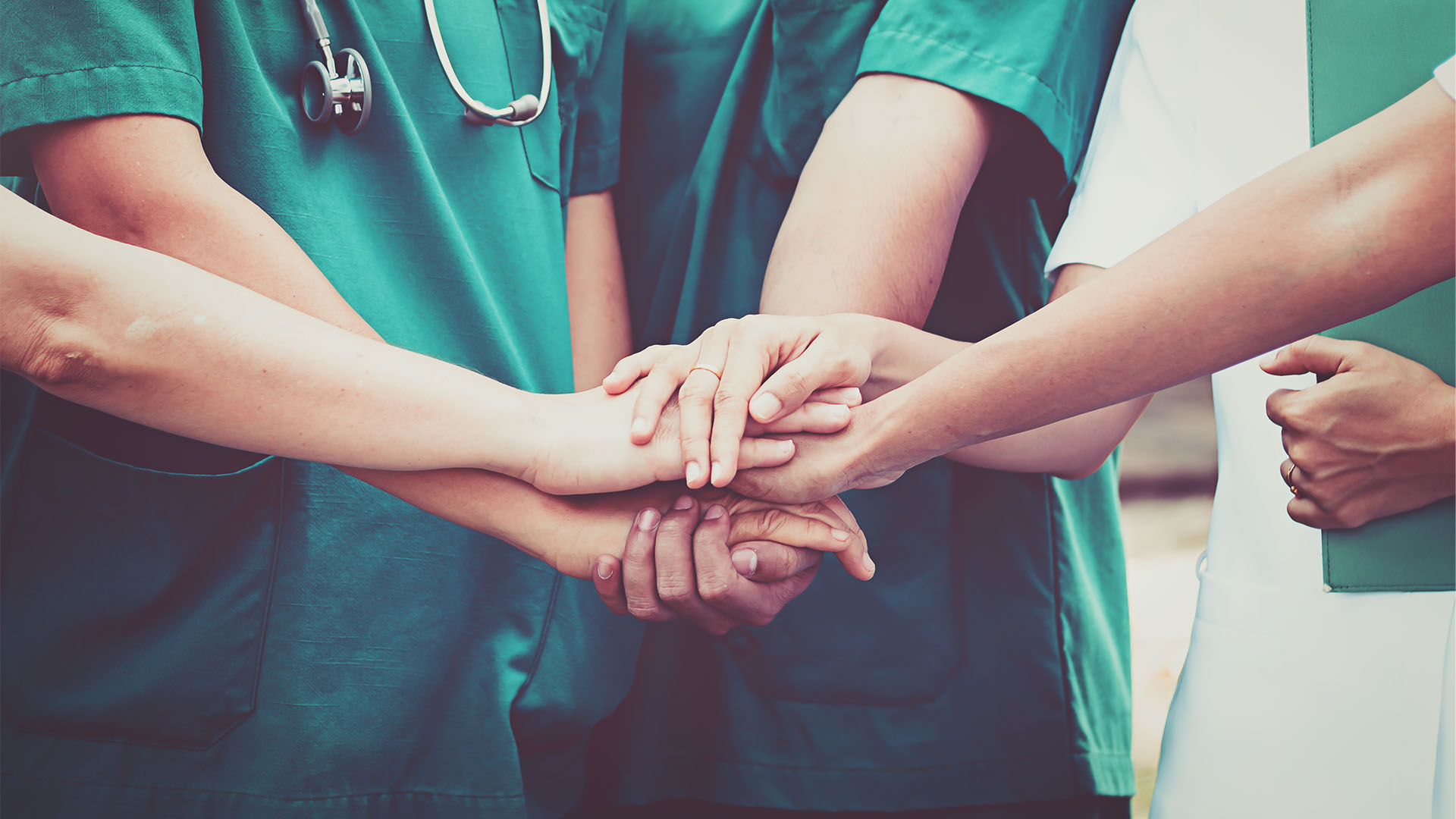 Group of Doctors and nurses coordinate hands.
